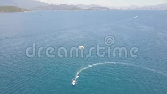 在蓝海湾无人驾驶飞机视野中带伞的帆船在绿松石海中滑翔伞航行的空中景色视频的预览图
