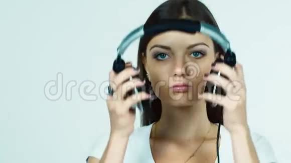 迷人的黑发女孩戴上耳机听音乐视频的预览图