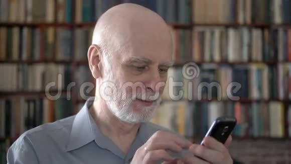 现代老人在家使用手机浏览阅读背景书架视频的预览图