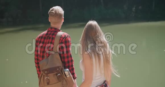 拥抱情侣站在森林中湖岸的后景视频的预览图