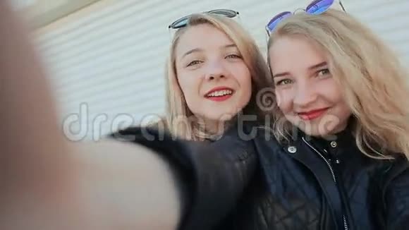 两个年轻漂亮的女朋友金发有趣和风骚在镜头前摆姿势做自拍春天视频的预览图