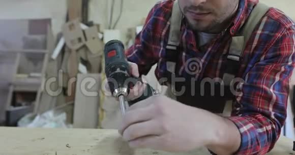 一个年轻的木匠用螺丝刀在家具生产中转动自攻视频的预览图