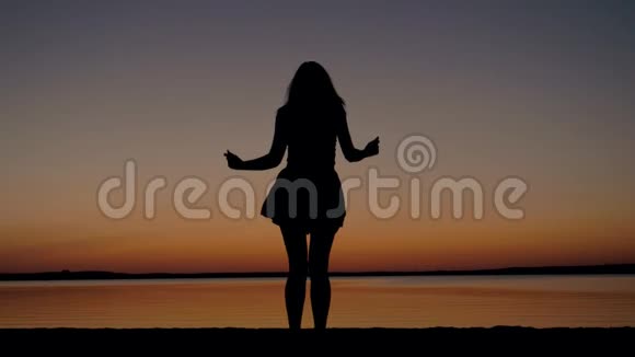 一个女人在海边夕阳下跳舞的剪影视频的预览图