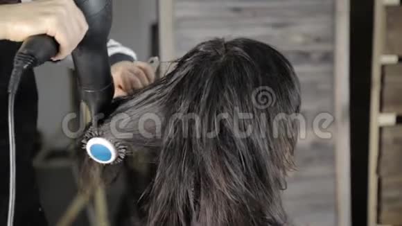 专业的理发师为漂亮的女性客户做头发造型使用带梳子的吹风机视频的预览图