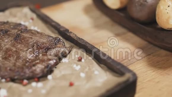 厨师正在用胡椒迷迭香和盐在木板上完成牛排关门视频的预览图