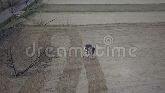 一名农民在一辆拖拉机上带着播种机在村庄地区的一个私人田地里播种谷物弹簧场的机械化视频的预览图