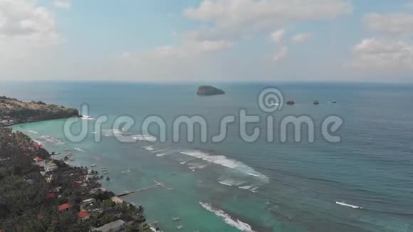 空中镜头飞越热带岛屿巴厘岛海岸线当地村庄和度假胜地走向海浪海洋视频的预览图