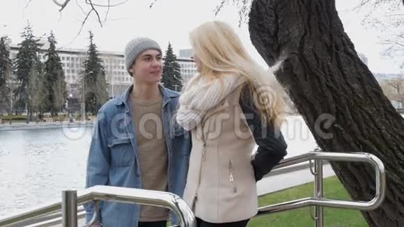 年轻漂亮的夫妇在约会站在池塘里的公园里金发女孩视频的预览图