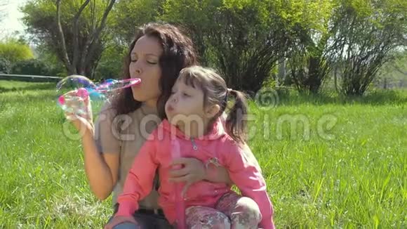 妈妈和女儿吹肥皂泡家庭在露天快乐的一家人在公园里玩泡泡视频的预览图