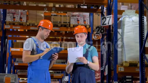 仓库工人在硬帽工作在仓库之间的仓库4K视频的预览图