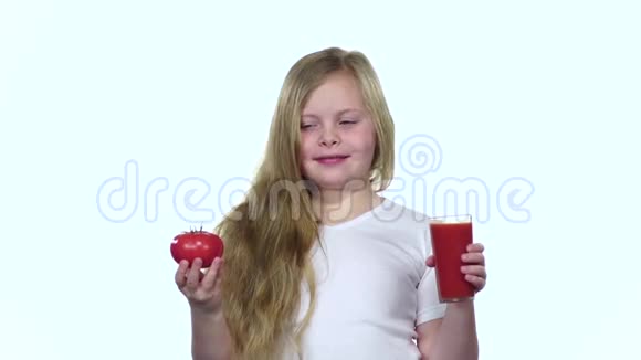 小女孩手里拿着一个西红柿闻起来很香白色背景慢动作视频的预览图