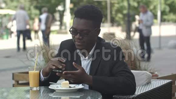 英俊的美国年轻商人使用智能手机给女友发信息在咖啡馆吃饭视频的预览图