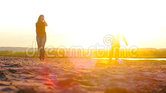 女孩和男人在海滩阳光下踢足球视频的预览图