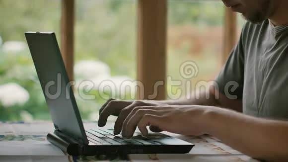 一个穿灰色T恤的男人正在一一个房间里工作房间里有一扇窗户可以俯瞰花园视频的预览图