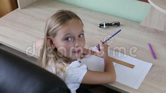 小女孩用铅笔在笔记本上用尺子画线回到学校的概念小女孩坐在桌子上待在室内视频的预览图