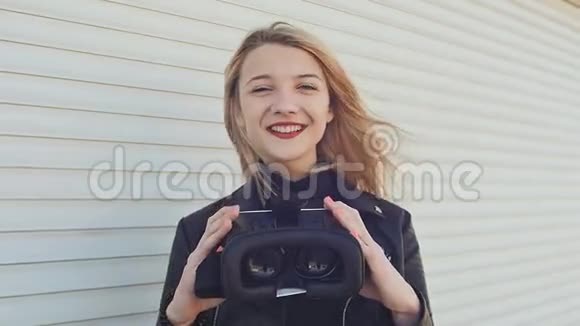 一个年轻时尚的金发女郎穿着皮夹克靠近水平滚筒百叶窗给相机带来虚拟眼镜视频的预览图