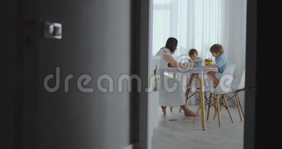 两个男孩的孩子和他的母亲坐在厨房里画画视频的预览图