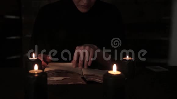 神秘美丽的修女穿着黑色的裙子修女读着一本带有黑色烛光的旧书视频的预览图