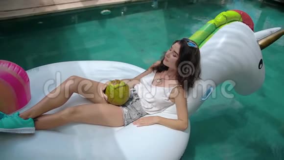 泳池里喝椰子水果的女人视频的预览图