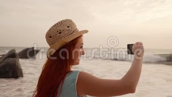 年轻的女游客在海边为日落拍照视频的预览图