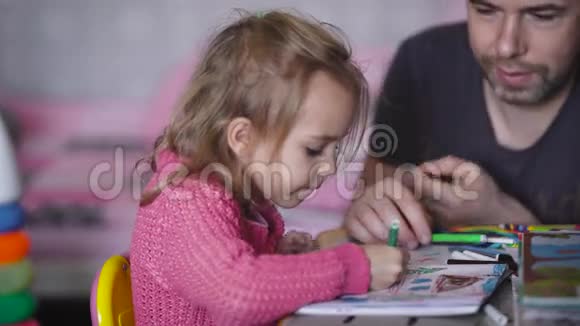 带着孩子的父亲的婴儿房间那个孩子和那个男人在一张画桌旁穿粉色夹克的女孩视频的预览图