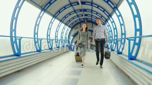 商业伙伴一男一女在车站或机场的终点站携带行李出差团队视频的预览图