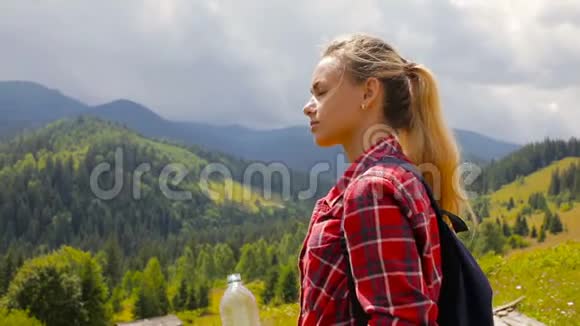 美丽的金发女孩在山里喝水视频的预览图