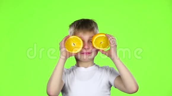 小男孩拿着一块橙色的薄片做各种鬼脸绿色屏幕慢动作视频的预览图