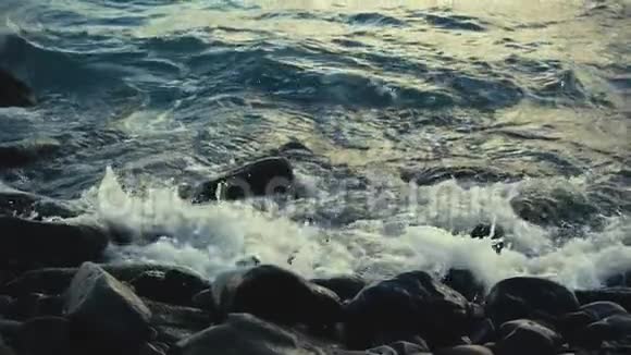 缓慢的波浪在岸边的岩石上破碎视频的预览图