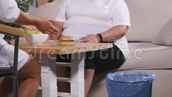 一个胖女人把一个汉堡扔进垃圾桶慢慢地选择一个苹果视频的预览图