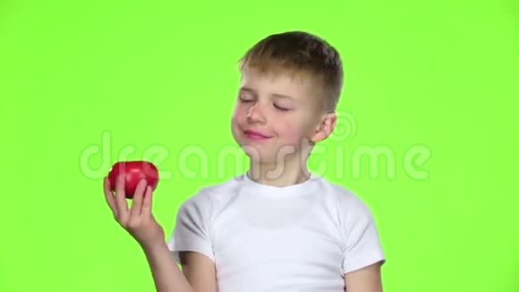 小男孩拿着番茄嗅着它竖起大拇指绿色屏幕慢动作视频的预览图