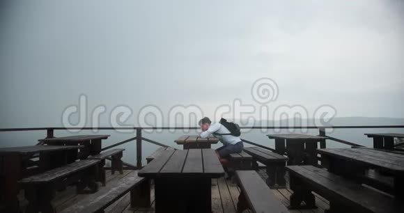 孤独的人在山里年轻的帅哥把头靠在手臂上坐在桌子旁视野很好视频的预览图