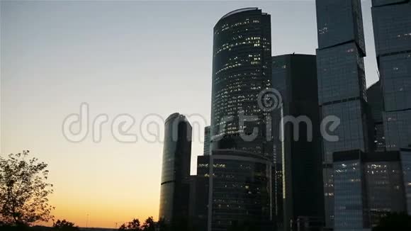 摩天大楼的玻璃立面在日落与阳光在天空现代城市商业区的现代建筑视频的预览图