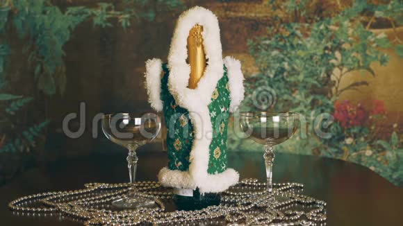 一条银链绕着一瓶香槟和两只玻璃杯旋转桌子上有一瓶香槟和酒视频的预览图