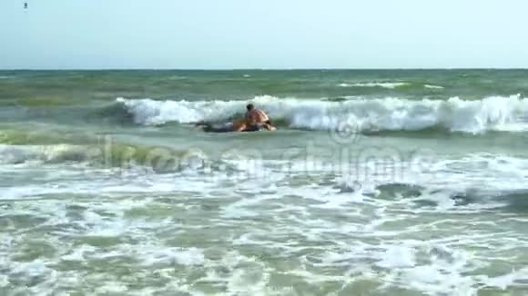 男人在充气床垫上在海里游泳他们在笑床垫在波浪上翻滚视频的预览图