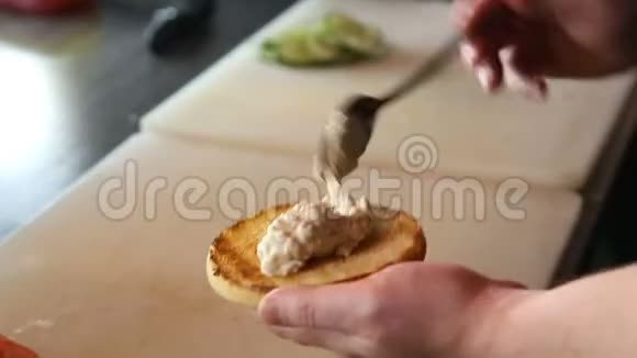 厨师用蘑菇酱铺一个汉堡包卷视频的预览图