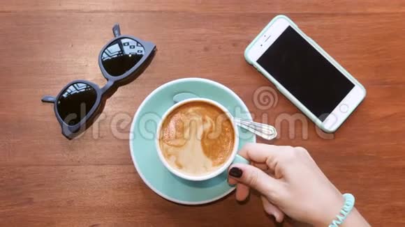 从木桌上拿咖啡的女性手杯小女孩喝咖啡和豆浆生活方式嬉皮士狡猾视频的预览图