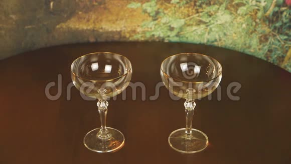 慢动作在木桌上向两个玻璃杯上倒入起泡葡萄酒香槟浪漫的晚间气氛视频的预览图