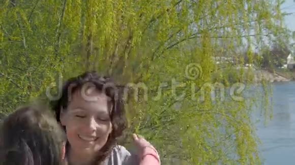 一个孩子在河岸上拥抱她的母亲幸福的家庭妈妈和女儿在新鲜空气中晴朗的一天视频的预览图