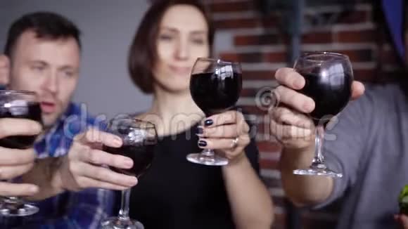 男人和女人的双手紧握着酒杯红酒相互碰撞背景中有着幸福的面孔集团视频的预览图