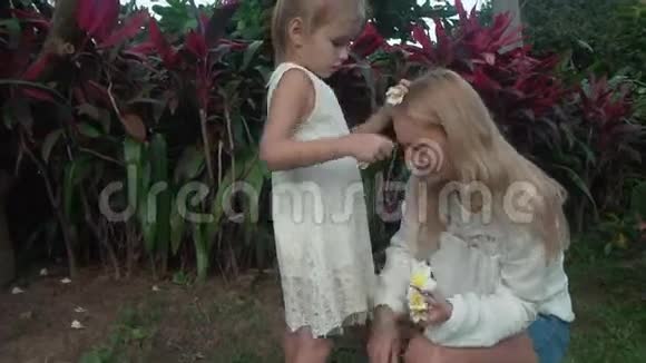 小女孩用梅花花装饰妈妈的头发视频的预览图