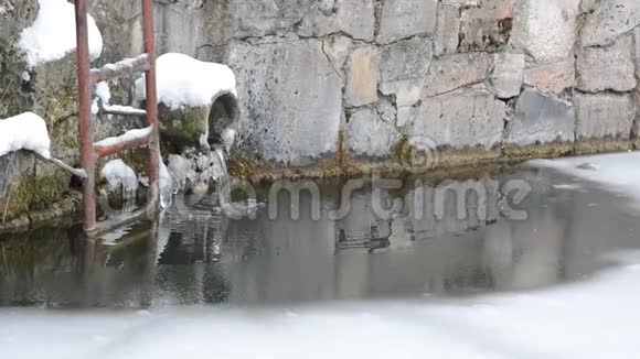 水从墙上流进湖里的管子冬天被冰冻住视频的预览图