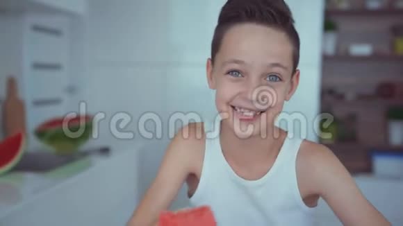快乐的男孩开胃地吃着红色的西瓜和在牙齿下流动的果汁视频的预览图
