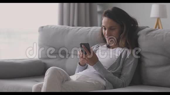 微笑混合种族的女人看着智能手机屏幕视频的预览图