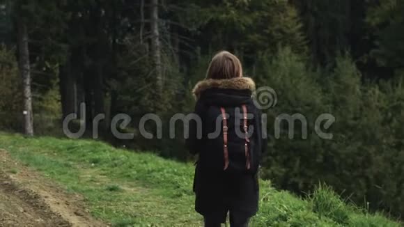 镜头跟随年轻女孩徒步旅行者在森林景观的背景下走在户外视频的预览图