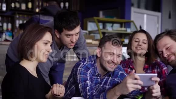 朋友们坐在咖啡馆的桌子旁一起度过闲暇时光使用数字小工具三个帅哥视频的预览图