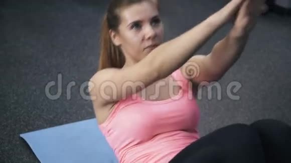 穿粉色衣服的女人在健身房做仰卧起坐视频的预览图