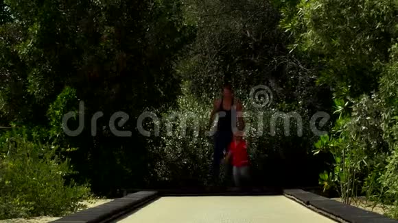 有趣的小男孩和妈妈一起在公园的蹦床跑道上奔跑和跳跃视频的预览图