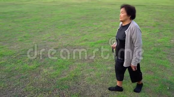 一位老妇人拿着拐杖在草地上散步视频的预览图