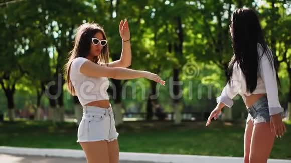周末两个穿着衣服的漂亮女孩骑在公园的赛格威上一边笑着跳舞视频的预览图